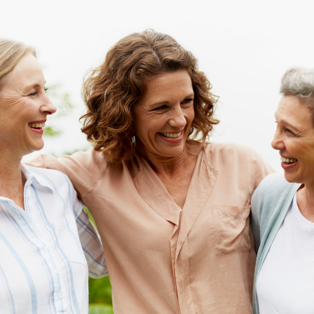 glückliche Frauen im mittleren Alter die sich in den Armen halten.